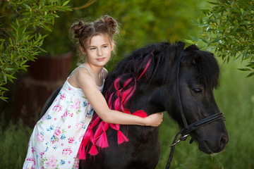 Cute little girl with black pony in the park