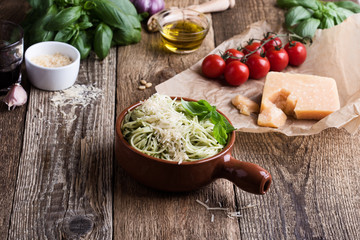 Vegetarian pesto pasta with cheese in bowl and Italian food ingredients
