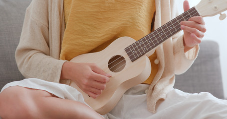 Fototapeta premium Woman playing song with ukulele at home