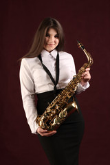 Young girl with saxophone in studio on dark background