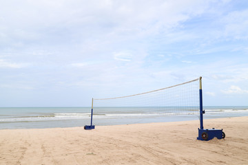 Fototapeta na wymiar Closeup of volleyball net on sand beach with sea and cloudy sky background. 