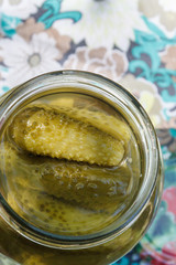 Pickles rolled in a glass jar stand on a wooden stump