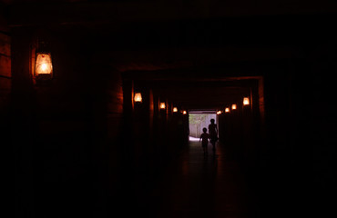 Two Silhouette Boys Children in Spooky Mysterious Hallway Mine Shaft with Eerie Golden Lantern Light