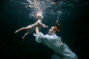 Mother teaches the baby to dive underwater.