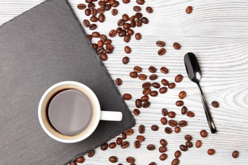 cup of coffee with coffee's beans over white wooden background, top view