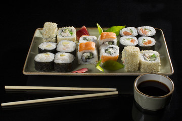 Menu of the Japanese restaurant. Several sushi lined on a plate with bamboo sticks and soy sauce.View of the rolls from above