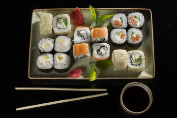Menu of the Japanese restaurant. Several sushi lined on a plate with bamboo sticks and soy sauce.View of the rolls from above