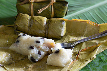 Suman, sticky rice stuffed with bananas, thai dessert on green banana leaf