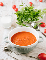 Bowl of homemade tomato soup with cream and parsley on wooden table. Copy spase for your text