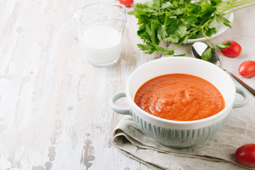 Bowl of homemade tomato soup with cream and parsley on wooden table. Copy spase for your text