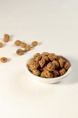Tigernuts / earth almonds / nutsedges in a small bowl, on white surface, copy space