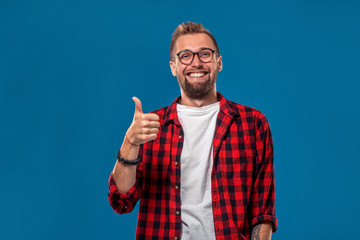 Naklejka premium Emotional and people concept: young bearded man in checkered shirt. Hipster style. The guy shows his hand - It's okay