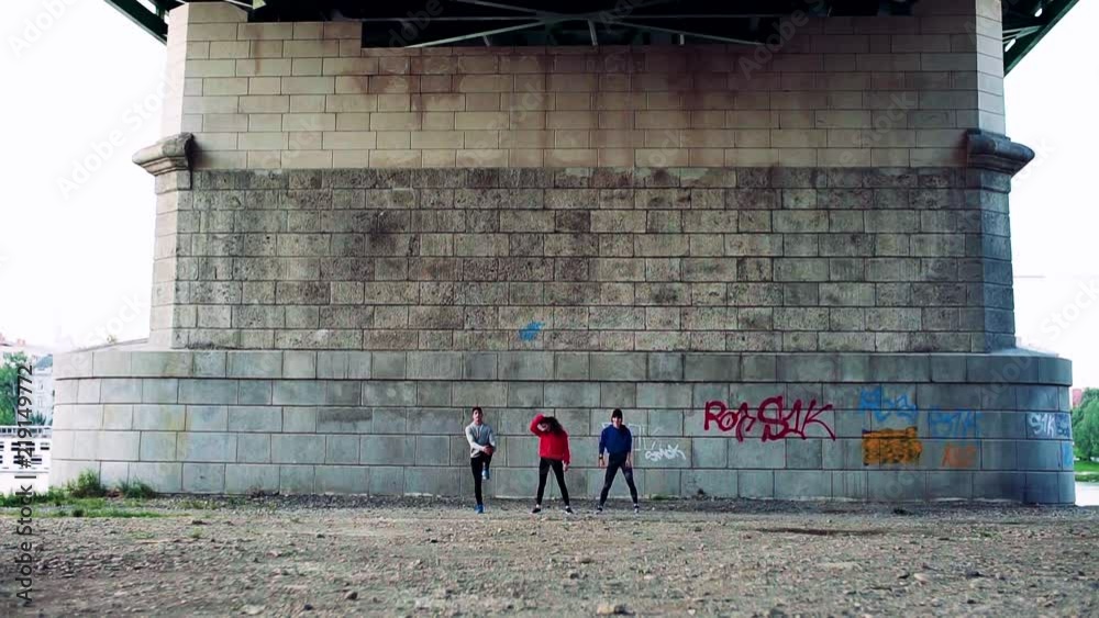 Sticker Young athlete friends stretching under the bridge in the city.