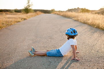 little boy in sport helmet sitting on empty highway road looking in to future