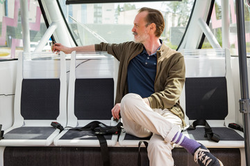 Interior of automated remotely operated bus in Helsinki. Unmanned public transport test on street. Passenger sitting on seat, waiting on bus stop. 