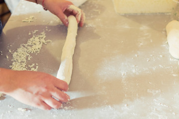 Fototapeta premium Preparation of a Georgian tube with cheese. The dough rolls out with grated cheese for baking.