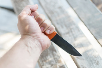 A knife in a man's hand. The concept of cruelty, violence, aggressive criminal behavior.