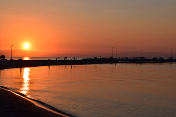 Beautiful sunset in Peraia, Thessaloniki Greece. Silhouettes walking on the shore
