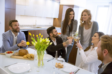 Young friends having dinner at home and toasting with white wine