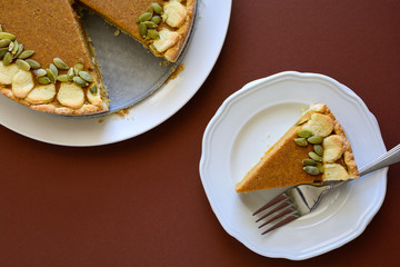 Homemade pumpkin pie with cinnamon on brown paper background. Thanksgiving day or Halloween holiday concept. Top view