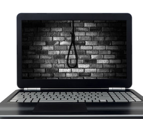 Black laptop pc showing picture of shadow from hanging suicide rope on brick wall