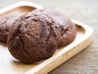 Homemade soft dark chocolate brownie cookies placed on a wooden plate. The cookies is look good and...