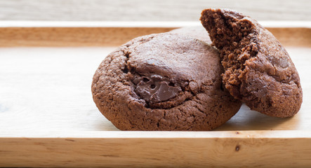 Homemade soft dark chocolate brownie cookies placed on a wooden plate. Close Up cookies are bitten. Look good and delicious.