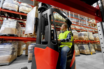 logistic business, shipment and loading concept - loader operating forklift at warehouse - obrazy, fototapety, plakaty