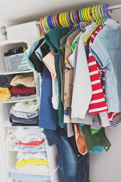 Toddler Boy Clothes Closet. Kids Clothes On Colorful Hangers And Side Shelves. Closet Organization Solution, Messy Closet, Real Life Not Staged. Matte Filter, Natural Lighting.