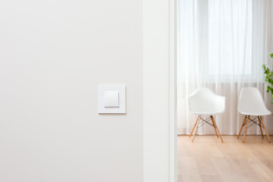Wall switch in light interior. Modern, beautiful, clean apartment in the background.