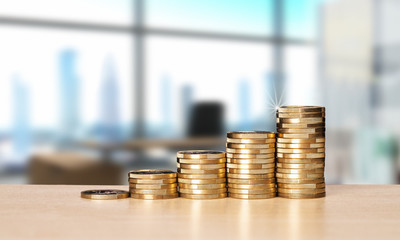 Stapel mit Münzen und Büro im Hintergrund