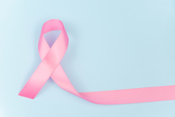 Pink ribbon symbol for breast cancer awareness concept on blue background with copy space for text,...