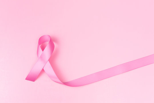 Pink ribbon symbol for breast cancer awareness concept over pink background with copy space for text, logo or wordings insertion or decoration