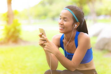 Sport woman closed eyes listten to the music on mobile phone in the park with happiness mind