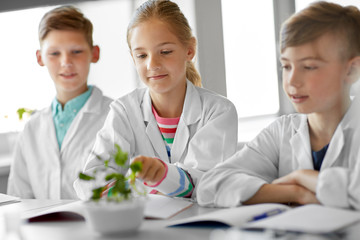 Obraz premium education, science and school concept - kids or students with plant at biology class