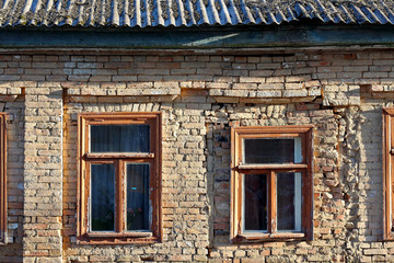 Fototapeta na wymiar Facade of the old house in emergency condition of red brick with old wooden windows