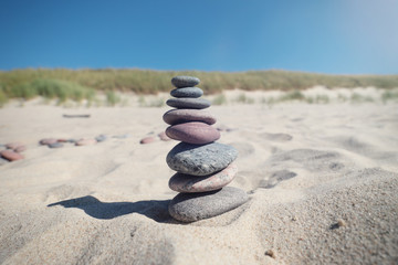 Fototapeta na wymiar Pyramid of sea stones on the sand by the sea