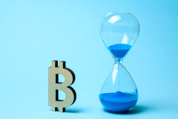 Hourglass and symbol of bitcoin on the table