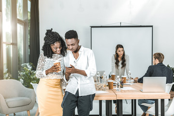 smiling african american business people using smartphone together in office