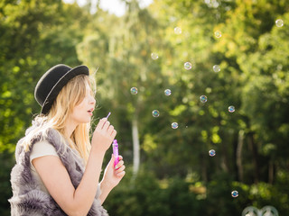 Joyful teen woman blowing bubbles