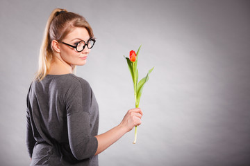 Seducive nerdy girl holding tulip.