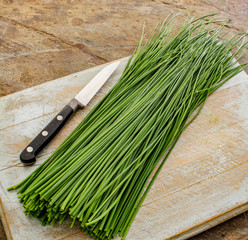 slicing fresh chives on chopping board