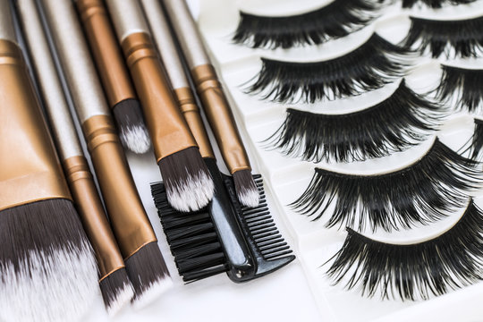 Professional brushes for make-up and set of false eyelashes on a white background