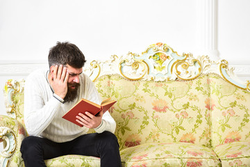 Scandalous bestseller concept. Guy reading book with attention. Man with beard and mustache sits on...