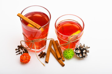 Glasses with mulled wine or hot drink tied with twine on white background, close up. Mulled wine or hot beverage in glasses with cinnamon sticks and fir cone. Christmas drinks concept