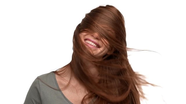 Portrait of joyful ginger woman 20s playing around and shaking her red hair, isolated over white background slow motion. Concept of emotions