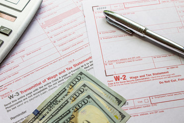 W-2 and W-3 filing forms as well as a calculator, pen and 3$100 bank notes
