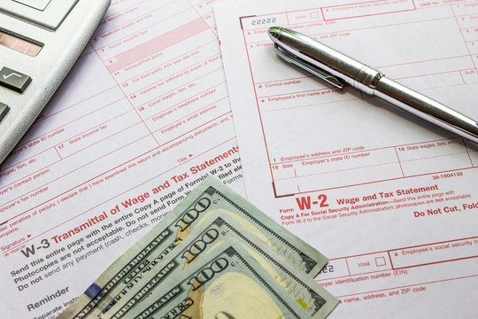 W-2 and W-3 filing forms as well as a calculator, pen and 3$100 bank notes