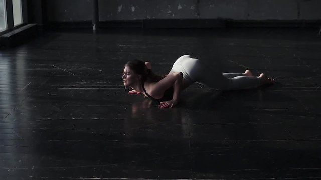 attractive young girl doing stretching in a spacious dark hall. slow motion
