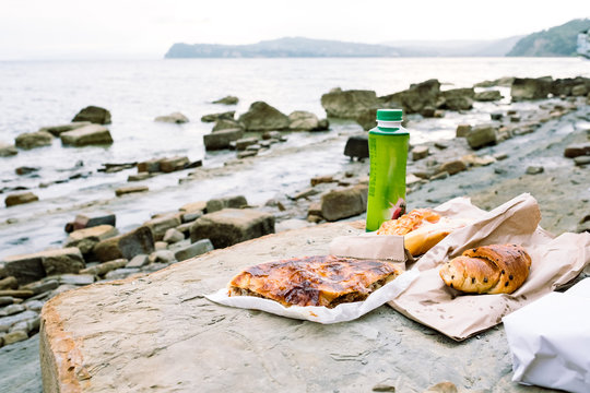 Outdoor picnic at the rocky beach with fresh pastry from local bakery, Slovenia typical food